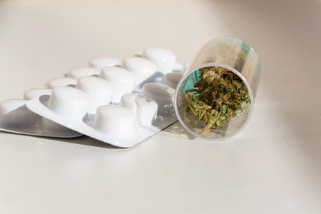 Medical marihuana, prescription cannabis in plastic bottle with painkiller pills, close up isolated on white backgroundの写真素材