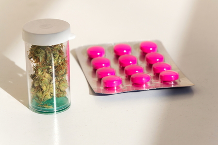 Medical marihuana, prescription cannabis in plastic bottle with painkiller pills, close up isolated on white backgroundの写真素材