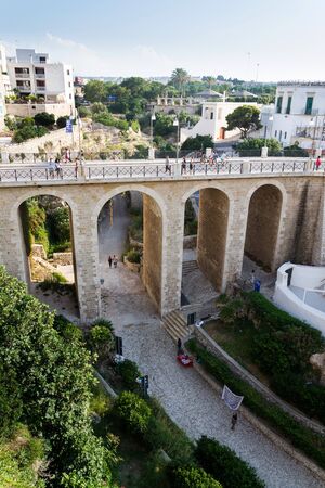POLIGNANO A MARE, ITALY - JULY 6 2018: People on the Ponte Lama Monachile bridge, Adriatic Sea, Apulia, Bari province on July 6, 2018 in Polignano a Mare, Italy.のeditorial素材