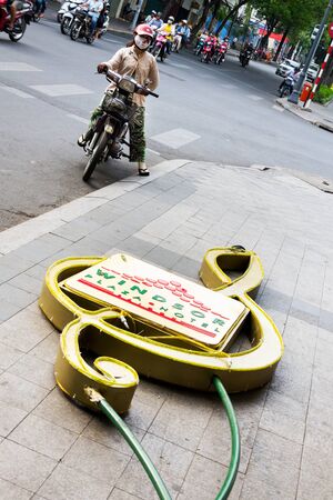 HO CHI MINH CITY - FEBRUARY 4: Woman on motorbike stands on busy street with Windsor Plaza Hotel neon sign in foreground on February 4, 2012 in Ho Chi Minh City, Vietnam.のeditorial素材
