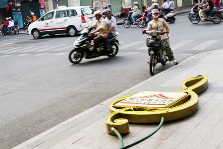 HO CHI MINH CITY - FEBRUARY 4: Woman on motorbike stands on busy street with Windsor Plaza Hotel neon sign in foreground on February 4, 2012 in Ho Chi Minh City, Vietnam.のeditorial素材