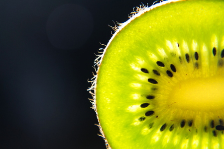 Green fresh kiwi fruit sliced piece stands backlit, healthy diet, new year resolution conceptの写真素材