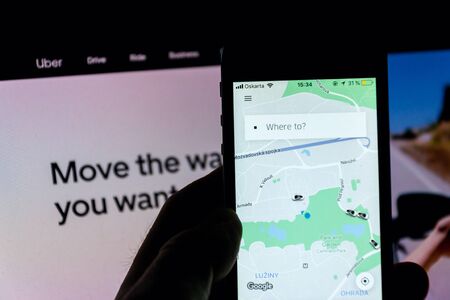 PRAGUE, CZECH REPUBLIC - NOVEMBER 21 2018: Uber company mobile app on phone screen with internet homepage in background on November 21, 2018 in Prague, Czech republic.のeditorial素材