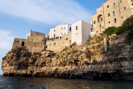 POLIGNANO A MARE, ITALY - JULY 6 2018: Tourist looking from view in historic center to lovely beach Lama Monachile, Adriatic Sea, Apulia, Bari province on July 6, 2018 in Polignano a Mare, Italy.のeditorial素材