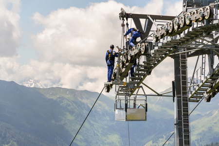 Two workers doing maintenance on cable car with Alps mountains in backgroun, Schonleitenbahn on Wildenkarkogel, Saalbach-Hinterglemm, Zell am See district, Salzburg federal state, Austriaの写真素材