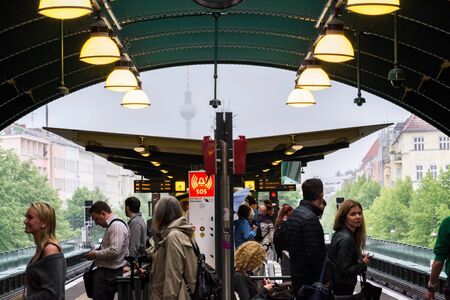 BERLIN, GERMANY - MAY 15 2018: People waiting for train of U-Bahn and S-Bahn rapid transit on station Schonhauser Allee with Fernsehturm television tower in foggy background on May 15, 2018 in Berlin, Germany.のeditorial素材