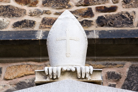 Three symbols of bishop, mitre with cross, gloves and book, in front of the Cathedral of St. Peter...