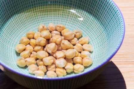 Chickpeas soaked in bowl with water before cooking to shorten cooking time, wooden table backgroundの写真素材