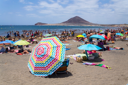 EL MEDANO, SPAIN - JULY 7 2019: People swimming and sunbathing on Playa El Medano beach on July 7, 2019 in El Medano, Spain.のeditorial素材