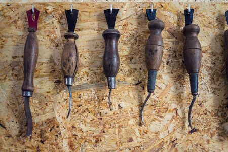 Group of old cobblers tools for handmade shoes production, awls and tongs for leather on wooden chipboard background, flat lay viewの写真素材