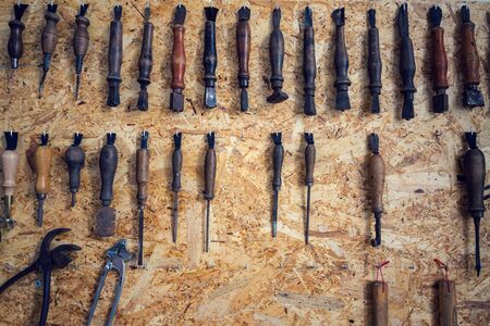 Group of old cobblers tools for handmade shoes production, awls and tongs for leather on wooden chipboard background, flat lay viewの写真素材