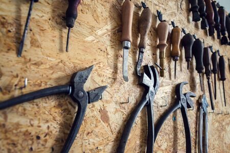 Group of old cobblers tools for handmade shoes production, awls and tongs for leather on wooden chipboard backgroundの写真素材