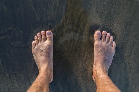 Human barefoot feet in wet sand on sea shore, active healthy living and personal growth concept, copy spaceの写真素材