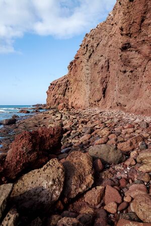 Dramatic red coloured cliffs on the coast of Montana Roja mountain near El Medano, Tenerife, Canary Islands, Spain, sunny summer dayの写真素材