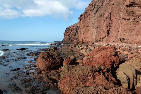 Dramatic red coloured cliffs on the coast of Montana Roja mountain near El Medano, Tenerife, Canary Islands, Spain, sunny summer dayの写真素材