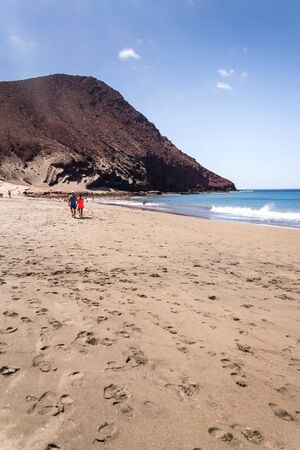 Unrecognizable people swimming, sunbathing and walking on La Tejita beach in Granadilla de Abona municipality, El Medano, Tenerife, Canary Islands, Spain, sunny summer dayの写真素材