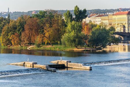 Strelecky Island with weir on Vltava river near National Theatre and the Charles Bridge, Prague, Czech Republic, sunny autumn dayの写真素材