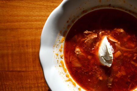 Plateful of hot borscht soup with beetroots, beef, pork, cabbage and carrots, sour cream on top,...