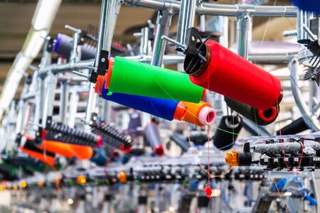 Colorful reel thread set up at modern and automatic sewing or embroidery spinning machine, textile industry factory concept の写真素材