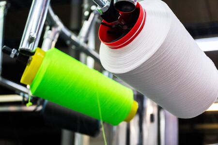 Colorful reel thread set up at modern and automatic sewing or embroidery spinning machine, textile...