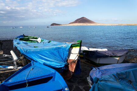 Traditional wooden fishing boats in El Medano harbour with Montana Roja in background, Tenerife, Canary Islands, Spain, sunrise on sunny summer dayの写真素材