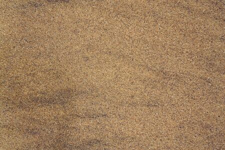 Wawes coming and leaving wet sand on sea shore, brown yellow and black grains from volcanic ash, zen background, harmony and meditation concept, flat lay top view, copy spaceの写真素材