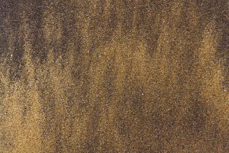 Wawes coming and leaving wet sand on sea shore, brown yellow and black grains from volcanic ash, zen background, harmony and meditation concept, flat lay top view, copy spaceの写真素材