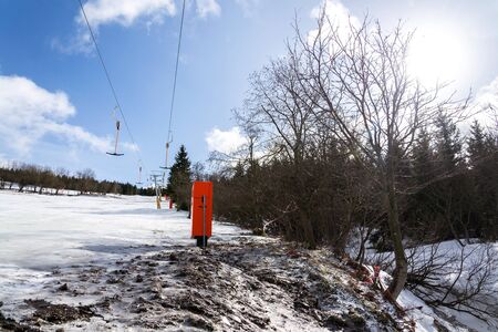 Stopped t-bar surface lift on empty piste, end of ski season concept, slope with disappearing snow,...