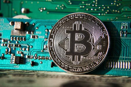 Silver bitcoin coin in front of computer motherboard, cryptocurrency mining and investing conceptの写真素材