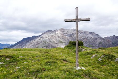 Cross on top of the mountains of Livigno Alps on the border between Italy and Switzerland, cloudy summer day, Italyの写真素材