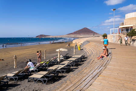 EL MEDANO, SPAIN - JULY 7 2019: People walking on promenade and surfing, kiting and windsurfing in Granadilla de Abona municipality on July 7, 2019 in El Medano, Spain.のeditorial素材