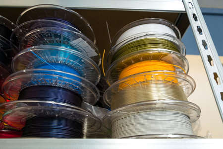 Stacks of 3d printing filament in different colors lying on metal shelfの写真素材