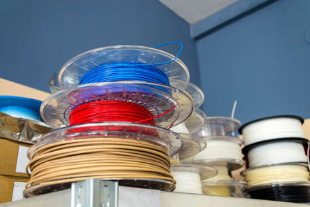 Stacks of 3d printing filament in different colors lying on metal shelfの写真素材