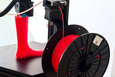 3d printer printing plastic last shoe prototype from red filamentの写真素材