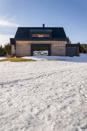 Wooden house with large reflective mirror window, design wall, modern architecture, sunny winter dayのeditorial素材