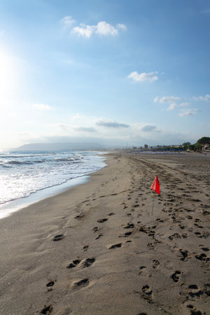 Empty beach with a red flag warning of big waves, sunny summer dayの写真素材