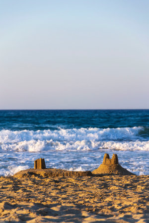 Beautiful sand castle on the beach at sunset, children's creativity, active vacation conceptの写真素材