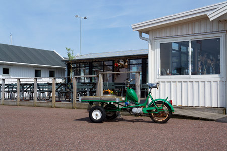 Flatbed moped parked on street of the peaceful car-free Vrango island with seaside village in Gothenburg archipelago, Vrango, Swedenの写真素材