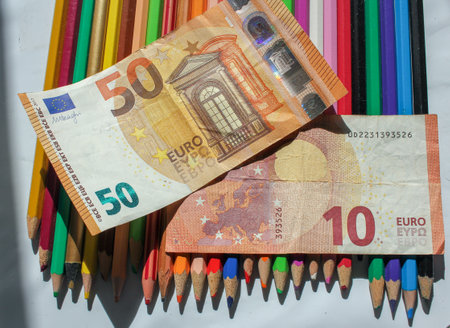 euro notes on colors pencils to pay for school suppliesの写真素材