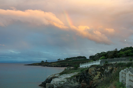 rainbow in a sunset over the Cantabrian sea with cloudy skyの写真素材