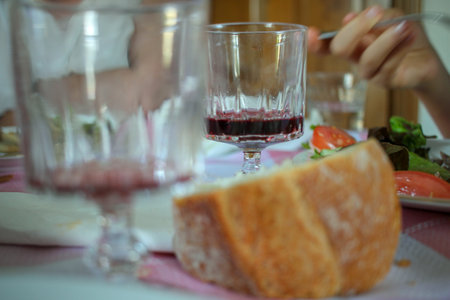 someone eating and two nearly empty glasses of wine on the table for dinner