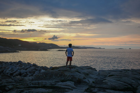 Childhood Wonder: Gazing at the Sea's Sunsetの写真素材
