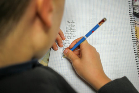 kid working and writing to do his homework after schoolの写真素材
