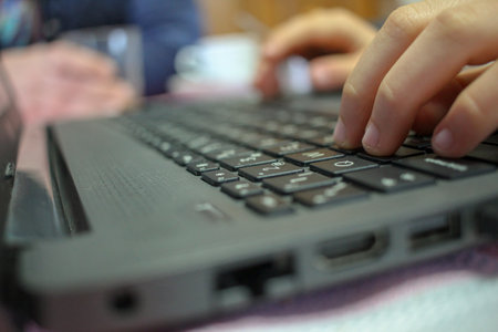 teenager pressing the keys of a laptop while his parents are having a cup of coffee