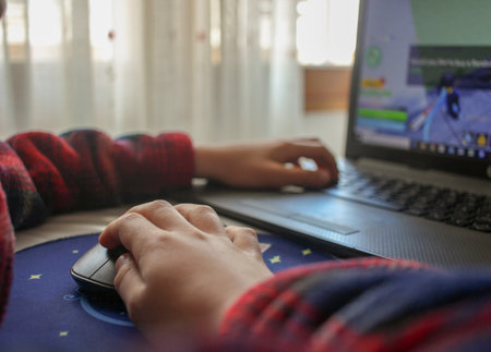 hands of a child playing games on a laptop at homeの写真素材