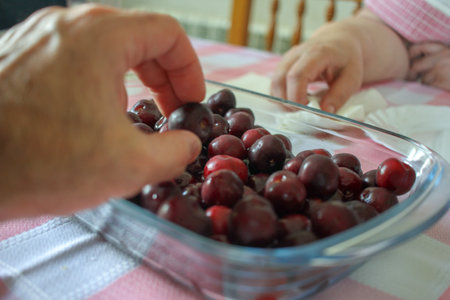two people eating cherries in a tray as a dessertの写真素材