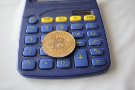 bitcoin on top of a blue calculatorの写真素材