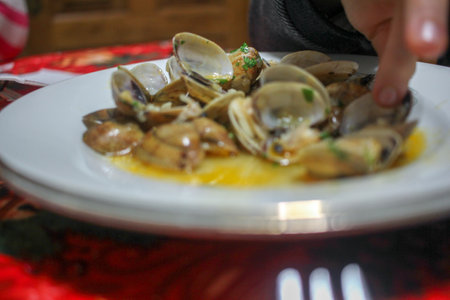 a boy is eating clams with his hands at homeの写真素材