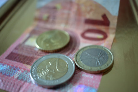 three coins and a bank note on a golden tray