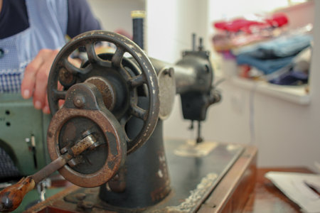 an elderly woman is working at home with an old sewing machine